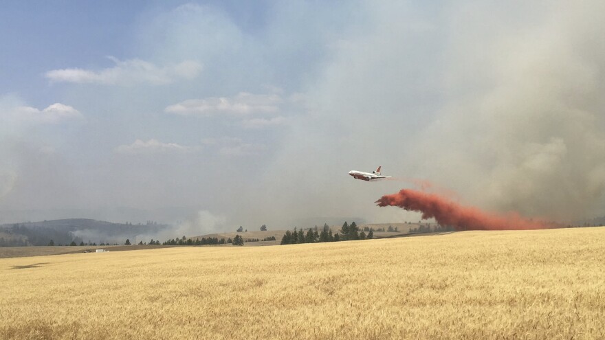 In this photo released by The Eastern Area Incident Management Team, a Very Large Air Tanker (VLAT) drops retardant on a wheat field as crews continue to battle a wildfire in eastern Washington state Sunday, Aug. 5, 2018.