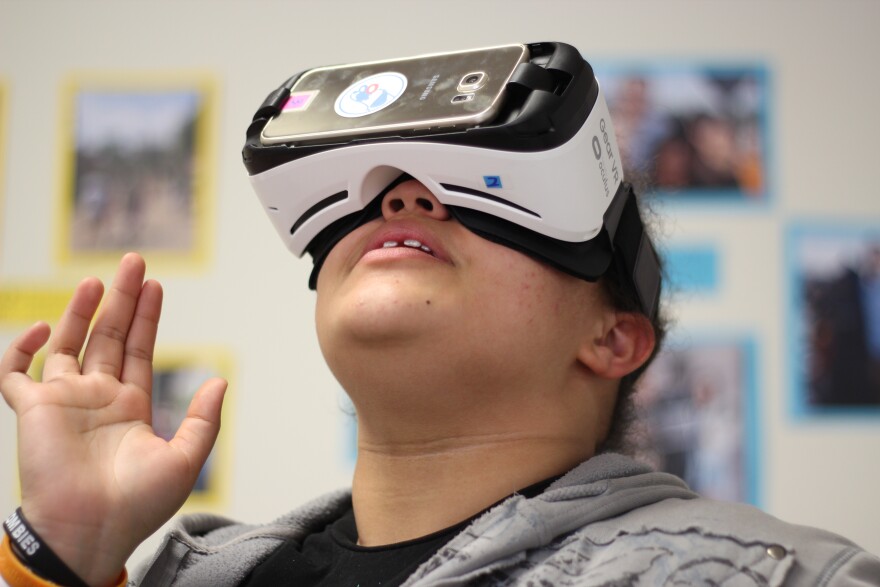 DeAnia, a junior in the College Bound program, looks around at works of art she can see through WoofbertVR virtual reality goggles.