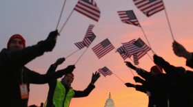 People wave American flags as they gather on the National Mall for the inauguration ceremony Monday.