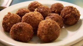 A close-up of golden fried croquetas balls on a white plate 