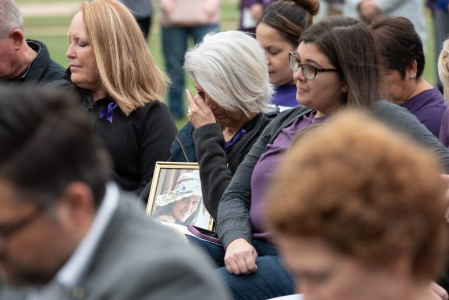 Julie Young, holds a photo of her daughter Michele Mayes, who was fatally shot by her ex-boyfriend in 2017. Mayes’ sister, Melissa Lindgren, right, and family friend Paula Cox, left, grieve for Mayes at a domestic violence awareness event in October. The 