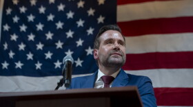 Josh Turek appears at a podium, in front of an American flag.