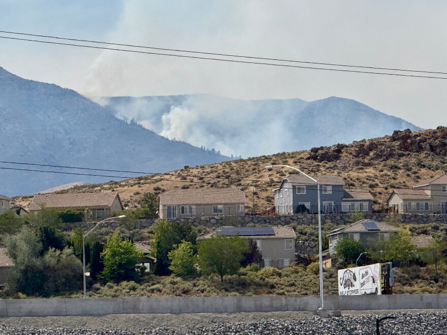 Smoke billows in the distance as a wildfire burns in Reno, Nev., Sunday, August 23, 2026. (AP Photo/Haven Daley)