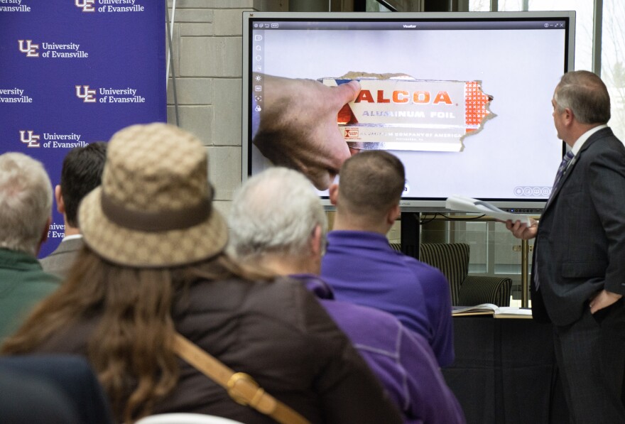 An overhead projector is used to share details of the time capsule items — such as a piece from an Alcoa Aluminum foil box.