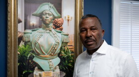 Norwalk Realtor Guy Bocicaut stands next to a photo featuring a bust of Haitian revolutionary leader Sanité Bélair at his offices in Norwalk on July 15, 2025. Bocicaut has called for a series of boycotts by immigrants and is seeking support from immigrant rights advocates.