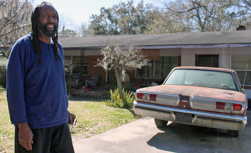 Andrew Miles stands outside the house he grew up in East Gainesville. He said he built the house next door and moved in after his mom died. He lives there with his fiance, Carla Lewis, and her son, Tyce, 14.