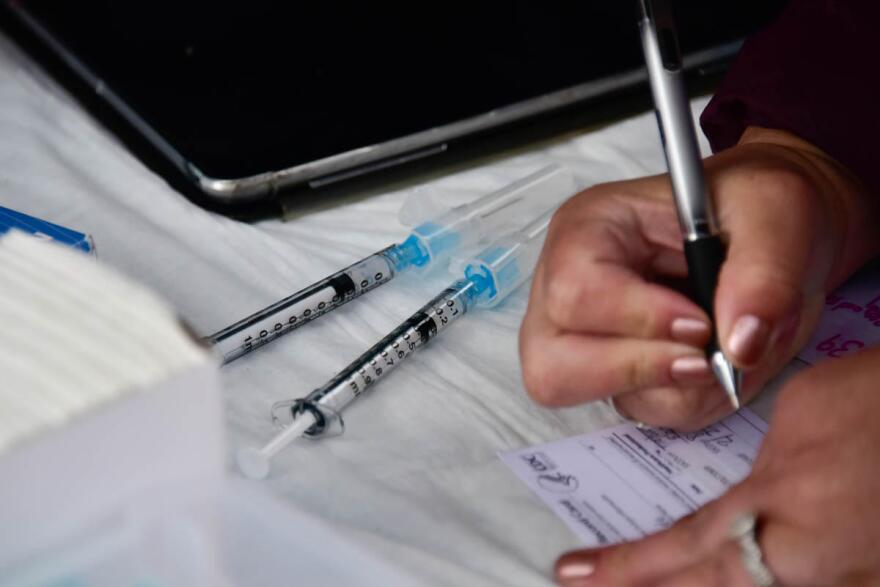 A worker at a COVID-19 vaccination clinic fills out paperwork.