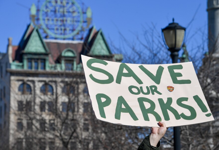 A man raises a sign that reads 'Save Our Parks' under the Scranton Electric building Saturday afternoon.