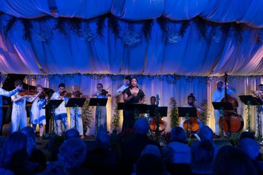 Laquita Mitchell with Palaver Strings on an outdoor stage in summer during the evening.