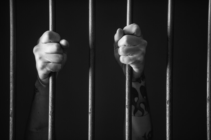 Hands holding a bar of prison