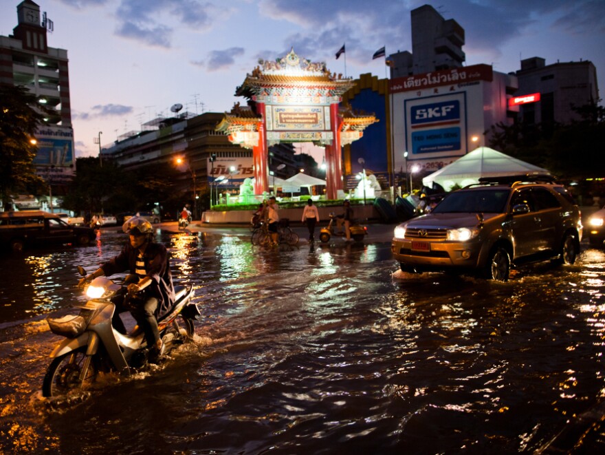 <p>Residents drive through a flooded street close to the overflowing Chao Phraya river in Bangkok on Thursday. About 400 people have died from floods in the country since late July. </p>