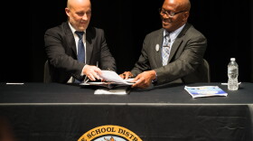 Lee County Schools Superintendent Greg Adkins trades papers with Lee County NAACP President James Muwakkil during the settlement agreement's signing at Dunbar High School on Aug. 21.