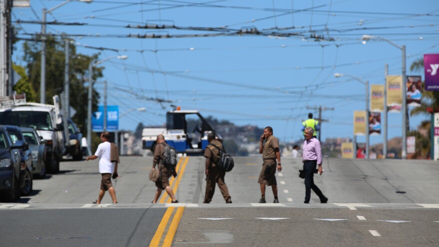 UPS employees cross the street shortly after a shooting at the company's facility in San Francisco. According to law enforcement, the suspect killed himself with a gunshot to the head.