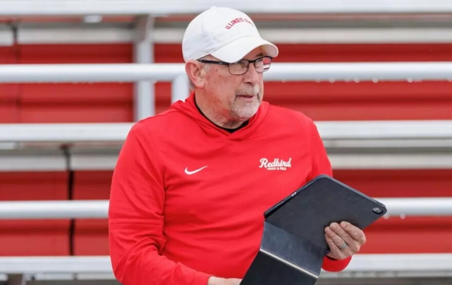 Older man in a red hoodie and white hat holding a computer tablet in his left hand.