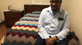 Timothy Lewis, a resident of the Oaks at 14th, sits on his bed that's covered with an afghan blanket he crocheted.