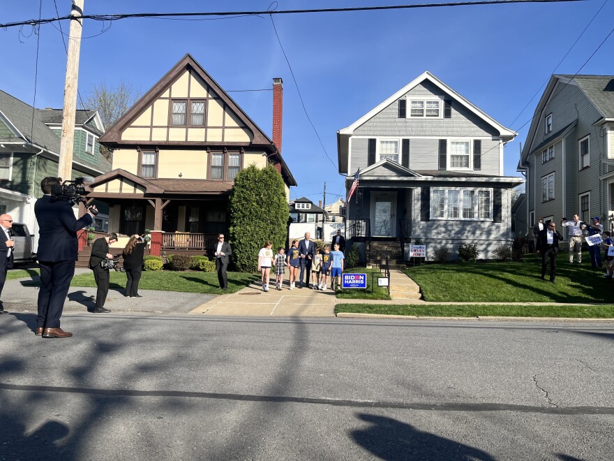 President Joe Biden walks out of his childhood home hand-in-hand with a group of young children.