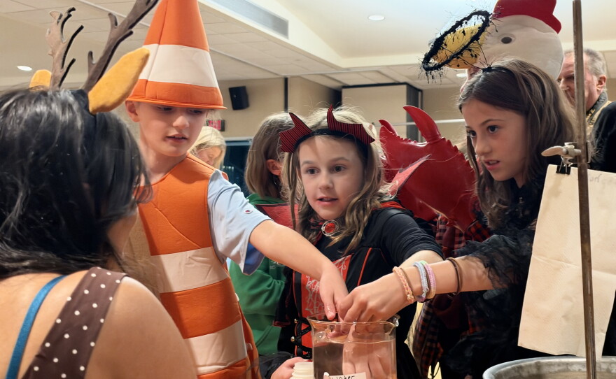 King's College students guide children in costumes through up-close chemistry at the “Things that Go Boom in the Night” Halloween event.