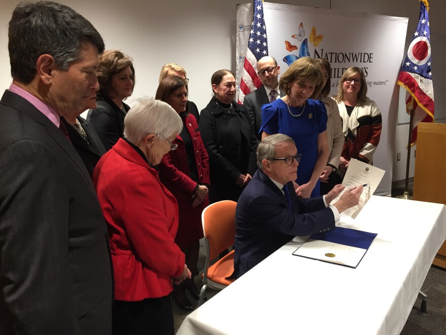 A photo of Mike DeWine signing an executive order