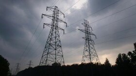 Power transmission lines shown against a sky of gathering storm clouds