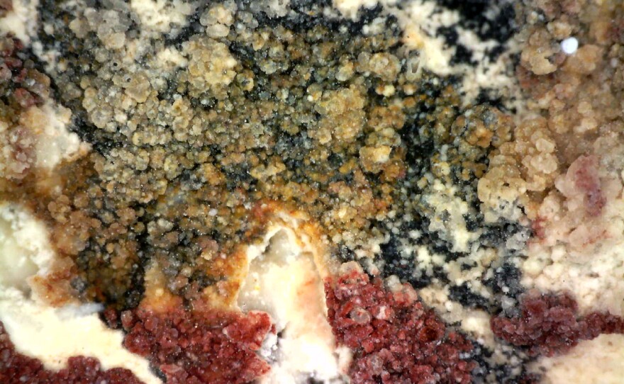 This photomicrograph, taken at Halo Shelter, shows the yellow over red over black paint layers. The black was applied first, then the red, then the yellow. The key to determining the order of paint layers is to examine the edges of each layer at the point s of intersection with another layer.