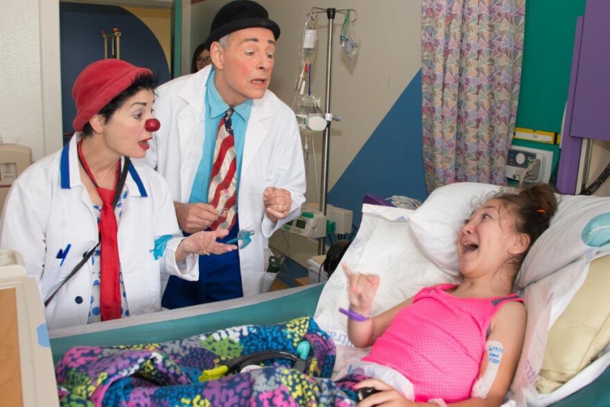 Doctors act as clowns to entertain a patient sick in bed at a hospital.