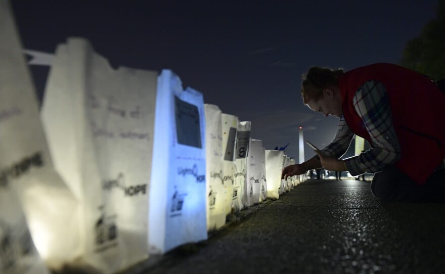 Dawn Scott of Cody, Wyo., a 20-year cancer survivor, photographs lighted bags in memory of friends and family who died of cancer during a "Lights of HOPE" ceremony in Washington, Tuesday, Sept. 25, 2018. (Susan Walsh/AP)