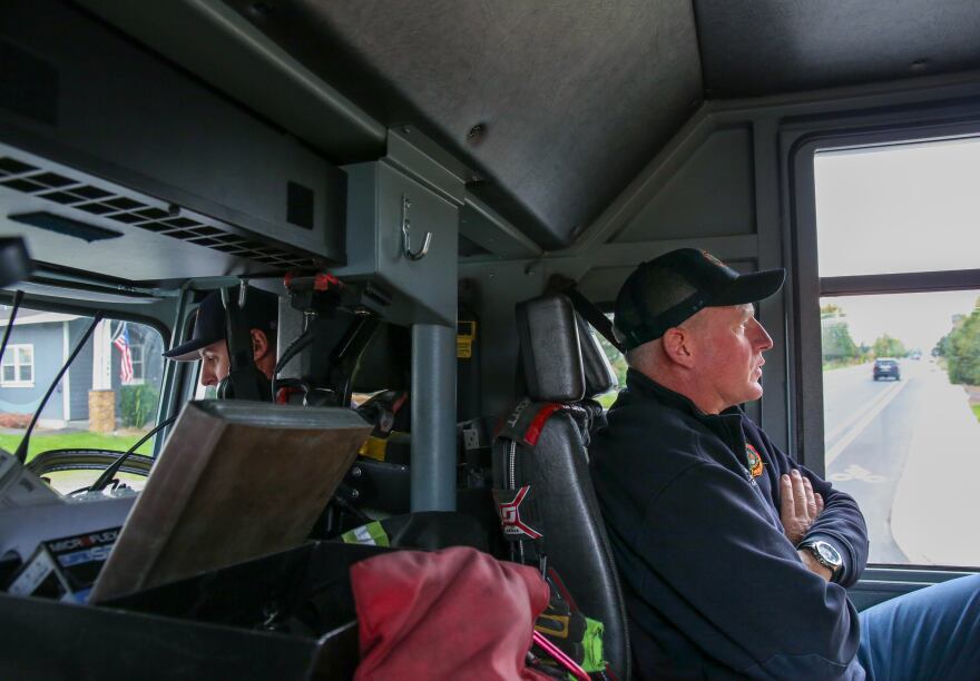 Two firefighters sitting in a fire truck.