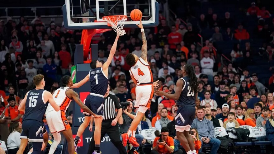 Syracuse guard Nate Kingz (4, White) finishes a layup beyond the reach of Monmouth forward Jason Rivera-Torres. (1, Navy)