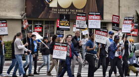 Picketers pass near a studio entrance during a Writers Guild rally outside Warner Bros. Studios. (Richard Vogel/AP)