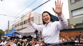 Woman waves to crowd on motorcade