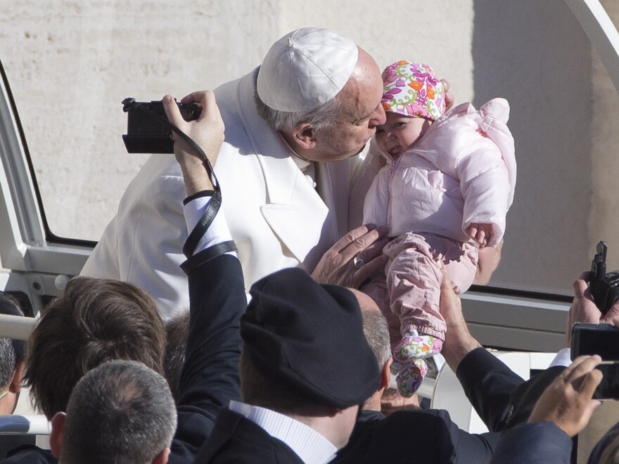 Pope Francis kisses a baby as he arrives for his weekly general audience in St. Peter's Square, at the Vatican, on Wednesday.