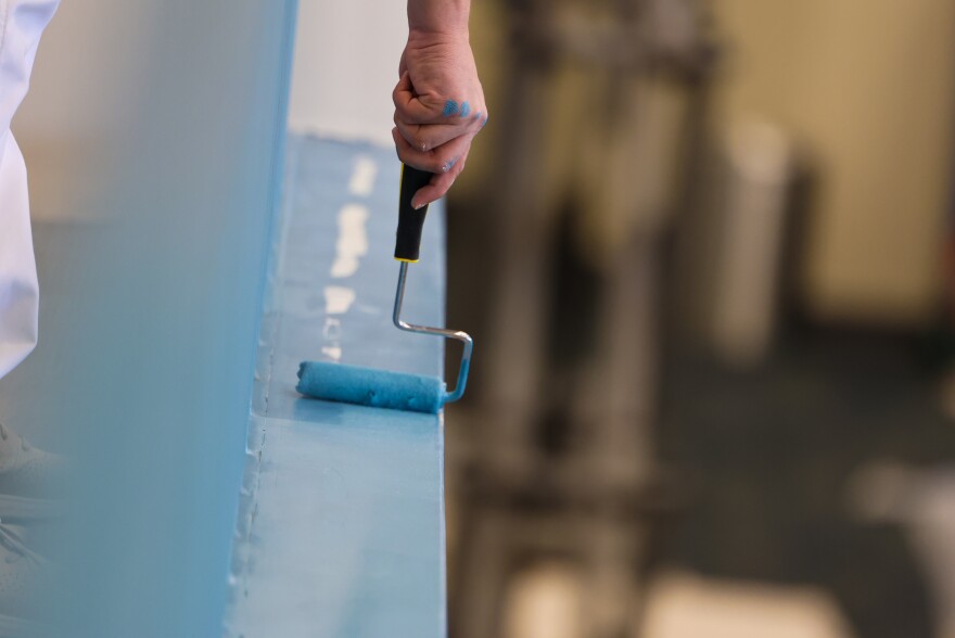 One of the volunteer paintings touches up the railing of the Gateway's lobby