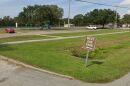 Picture of a parking lot with a West Dog Park sign in the foreground