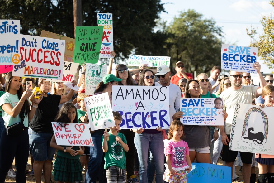 Students and parents hold signs asking for support for their schools and against closures. 