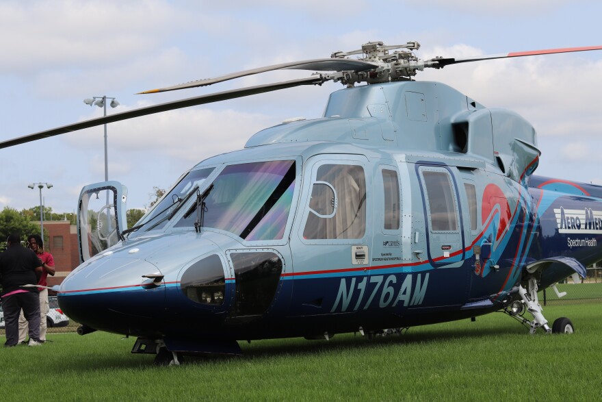 A large dual-toned blue Aero Med helicopter lands on a grass field.