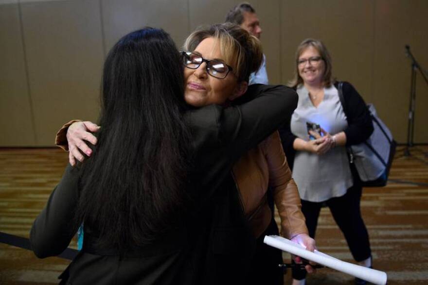 Sarah Palin and Mary Peltola hug before a candidate forum on Wednesday at the Alaska Oil and Gas Association convention in Anchorage.