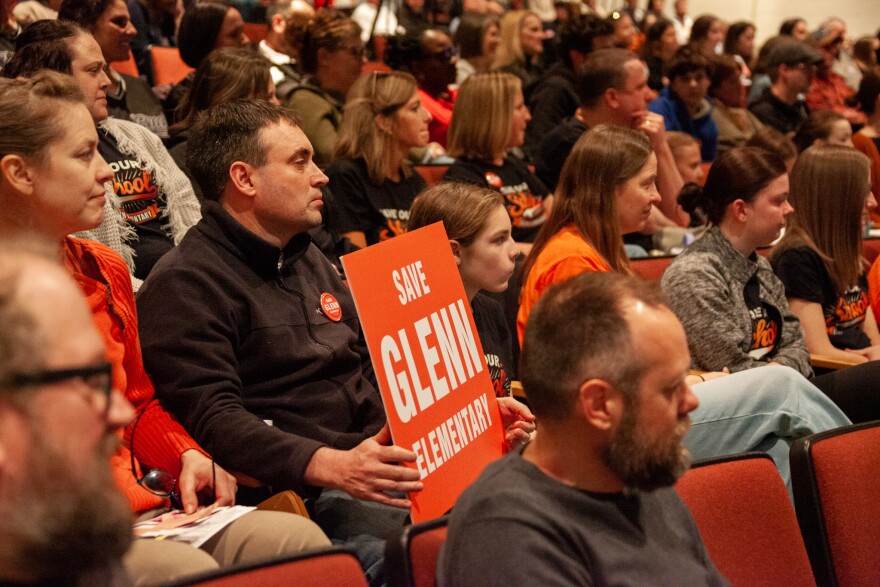Parent Kevin Bersett holds a sign during Wednesday's school board meeting