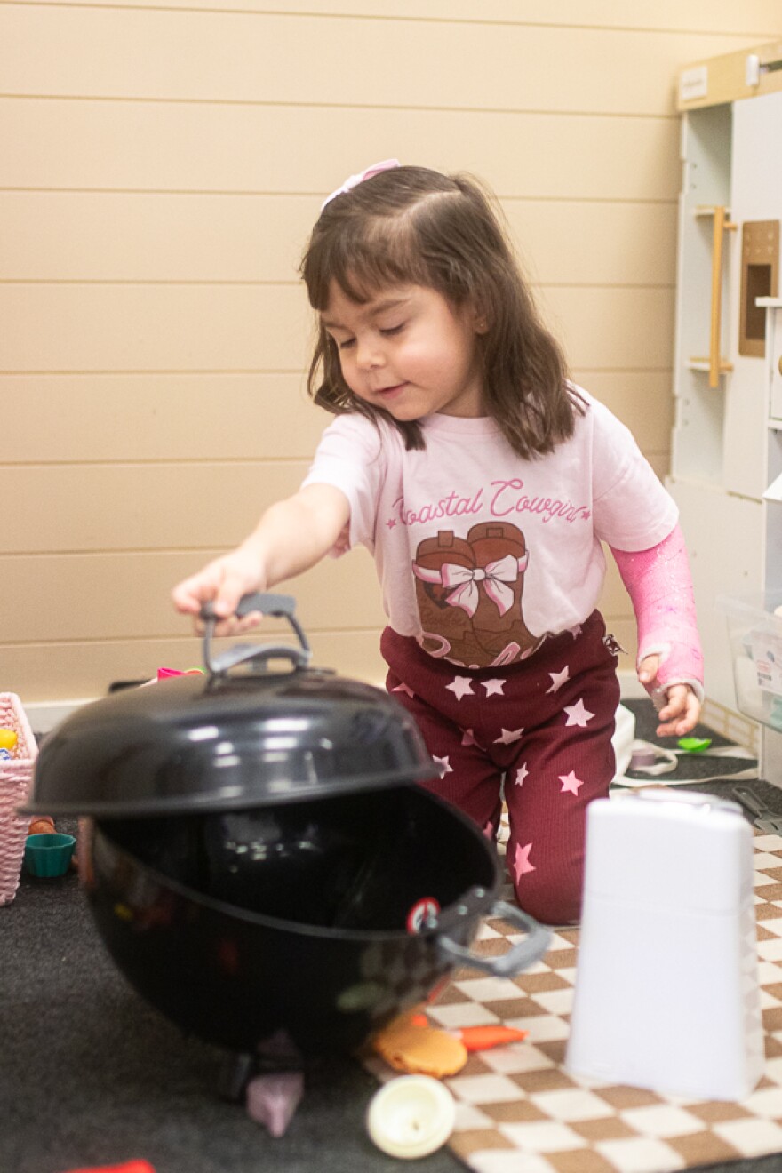 Aly Martinez plays with a toy grill on Feb. 26. There is a play kitchen with toy food for the kids to play with.