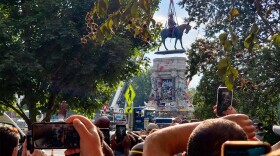 Onlookers crowd around the Lee Monument in Richmond watch as crews remove the statue from the pedestal Wednesday. (Ned Oliver/Virginia Mercury)