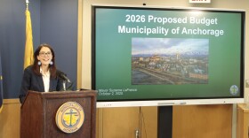 a smiling woman stands by a screen