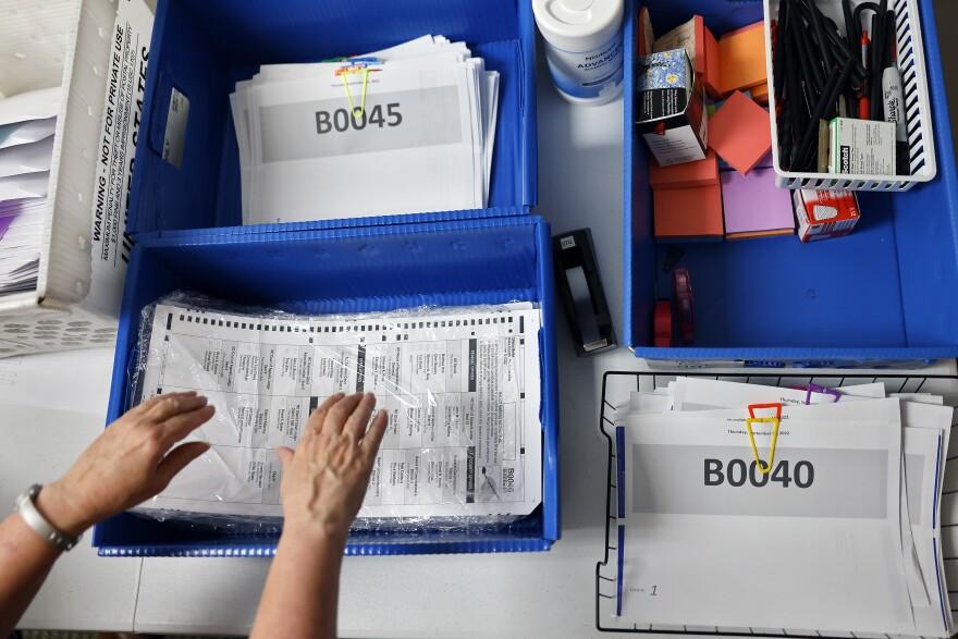 Cindy Hinkle reaches for a stack of ballots as election workers prepare to mail out absentee ballot requests at the Wake County Board of Elections office in Raleigh on Thursday, Sept. 15, 2022.