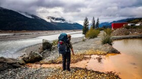 A man stands in front of acid mine drainage from British Columbia’s Tulsequah Chief Mine, which has been leaching acid mine drainage into the transboundary Taku River since it was abandoned in 1957.