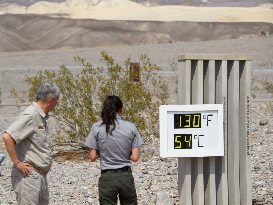 Park staff take pictures of a thermometer display showing a temperature of 130 degrees Fahrenheit on June 17, 2021, at the Furnace Creek Visitor Center at Death Valley National Park in California.