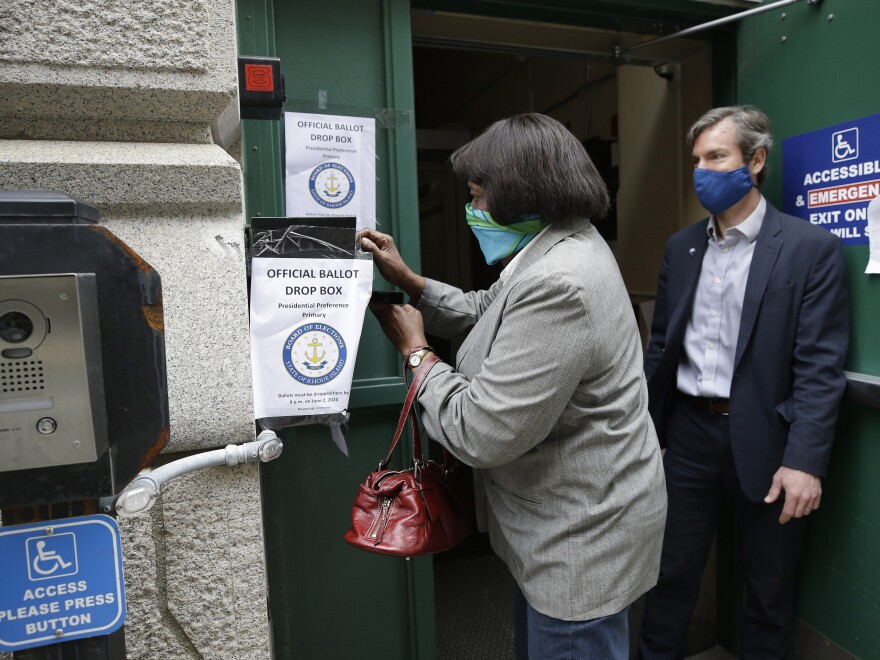 A voter places a ballot in a secure box in Providence, R.I., in June for the state's presidential primary. The U.S. Supreme Court says the state can suspend its witness or notary requirement to vote by mail in the fall elections.