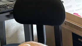 tabby kitten in foreground on chair with a tiger stripe kitten on desk behind him