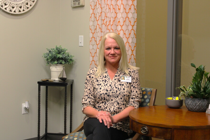 Executive Director Holly Wayland-Hall sits on a chair, legs crossed, with her hands in her lap.