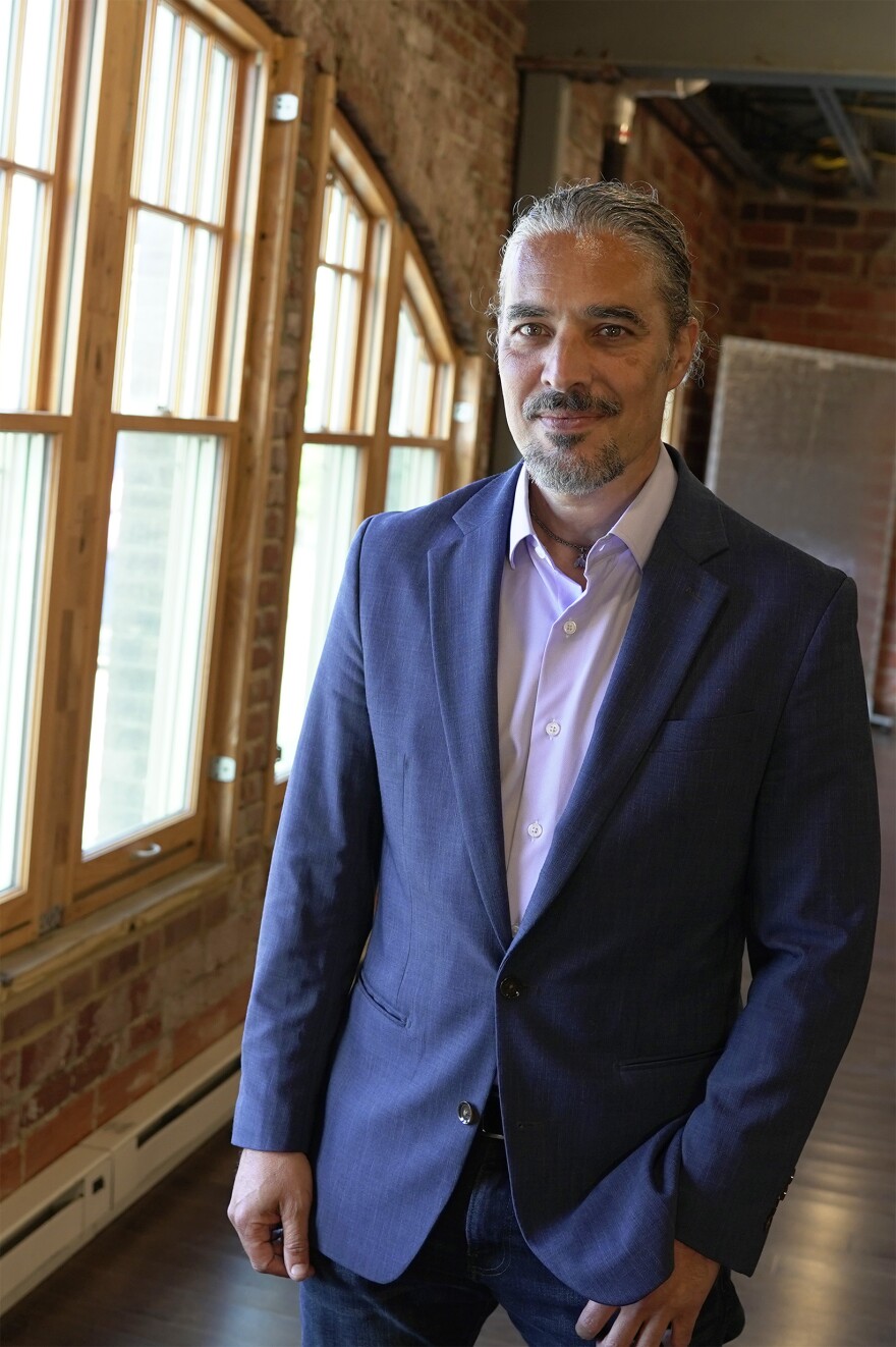 A man in a suit poses by a window