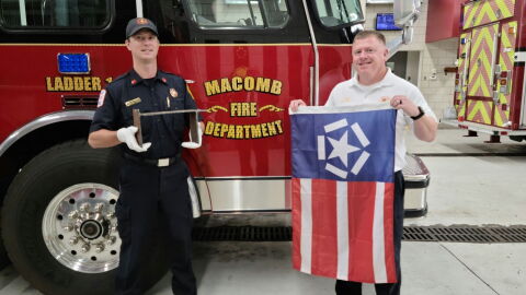 Lt. Ethan Taylor (left) holds the remnant from the World Trade Center, while Chief Dan Meyer displays the Freedom Flag.
