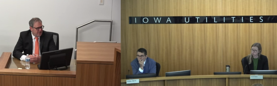 A Black Hills Energy official testifies at a hearing before the Iowa Utilities Commission in Des Moines as two commissioners listen from the front of the hearing room.