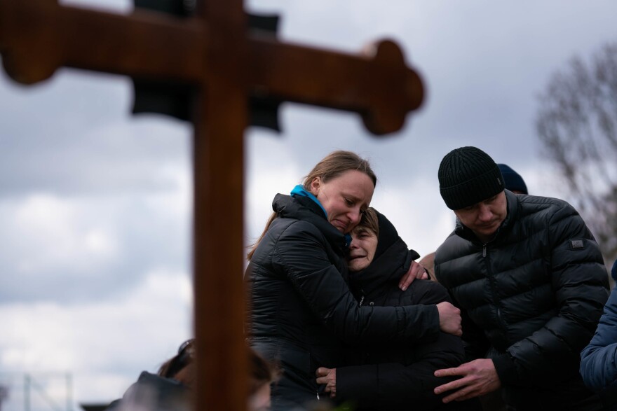 The mother (center) of Ukrainian journalist-turned-soldier Viktor Dudar grieves at his grave as he's laid to rest in Lviv in March, as some of the first dead soldiers' bodies are returned home.